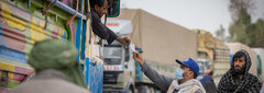 KANDAHAR, SOUTHERN AFGHANISTAN, An IOM staff distributes assistance cards to Afghans returning through Spin Boldak border crossing.