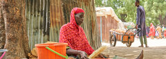 Borno state, Nigeria, Fatima Abah filters grain bought from a few harvests sold in the Bama IDP camp.