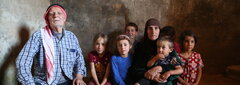 North-west Syria, An older man and woman sitting with children in a cave where they took shelter from hostilities.  