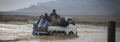 KANDAHAR, SOUTHERN AFGHANISTAN, A deported family navigates heavy rain and floods on their way to the IOM
transit center in Kandahar.