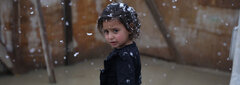 Bekaa Valley, Lebanon , Aisha stands in the snow in front of her flooded tent in an informal refugee settlement. 