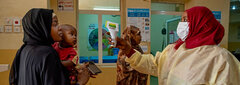 Khartoum, Sudan,  Nurse Nour (right) takes Mara’s temperature as she enters Omar Ibn Khatab Primary Health Centre. Nour attended a training workshop on infection prevention and control as part of the COVID-19 response. “Before, we were afraid,” she said. “The training helped me understand how to protect myself and my family from COVID-19.” 