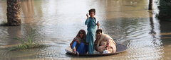 Larkana District, Pakistan, A boy uses a large cooking pan to ferry people from a flooded community in Larkana District, Sindh Province. 