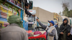 KANDAHAR, SOUTHERN AFGHANISTAN, An IOM staff distributes assistance cards to Afghans returning through Spin Boldak border crossing.