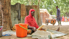 Borno state, Nigeria, Fatima Abah filters grain bought from a few harvests sold in the Bama IDP camp.