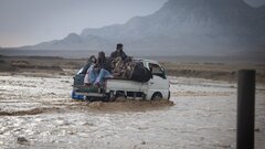 KANDAHAR, SOUTHERN AFGHANISTAN, A deported family navigates heavy rain and floods on their way to the IOM
transit center in Kandahar.