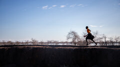 Rubkona, Unity State, South Sudan, A young girl running past a dyke built to protect communities from the flooding.