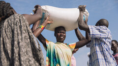 Malakal PoC site, Upper Nile State, South Sudan, An IDP woman carries a sack of sorghum she received during general food distribution.